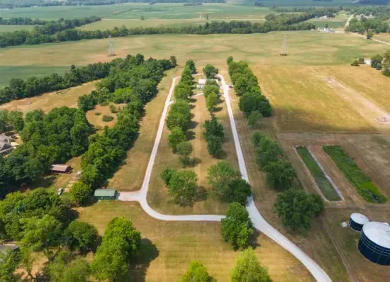 Expansive lot on 13 sprawling acres with an ATV loop, walking/running trail, 8 RV hookups ups, and flexibility to use as an event venue
