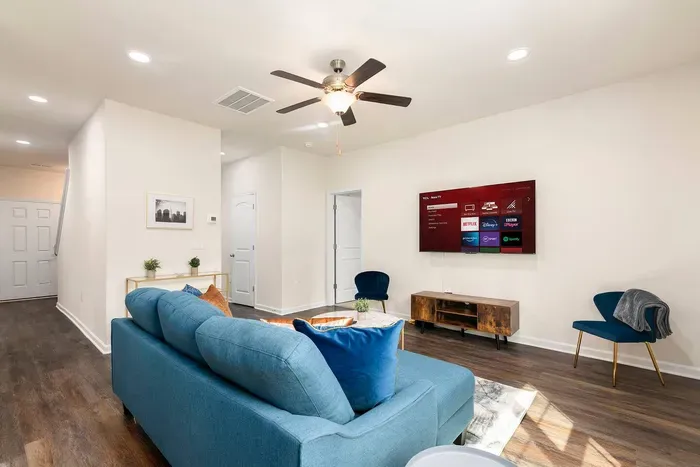 Stylish living room with a plush blue sofa, modern decor, and a 65 inch Roku TV.