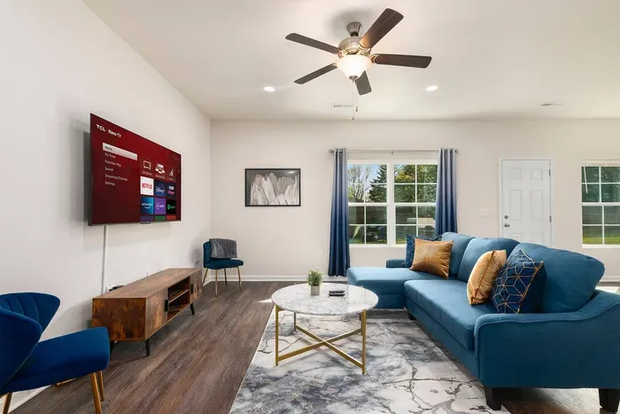 Stylish living room with a plush blue sofa, modern decor, and a 65 inch Roku TV.