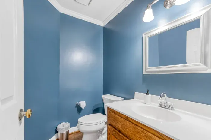 A stylish half bathroom with deep blue walls, a classic white vanity, and elegant lighting — perfect for guests and a nice pop of color in the home.