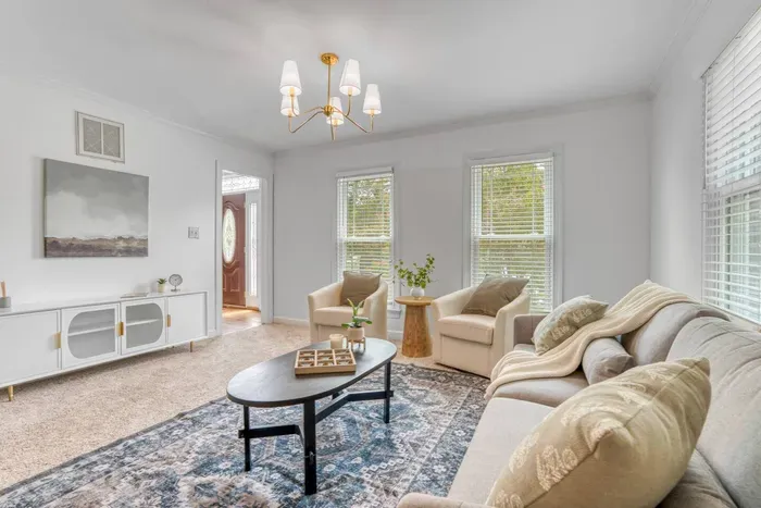Living room with neutral tones, cozy seating, and a stylish modern chandelier.