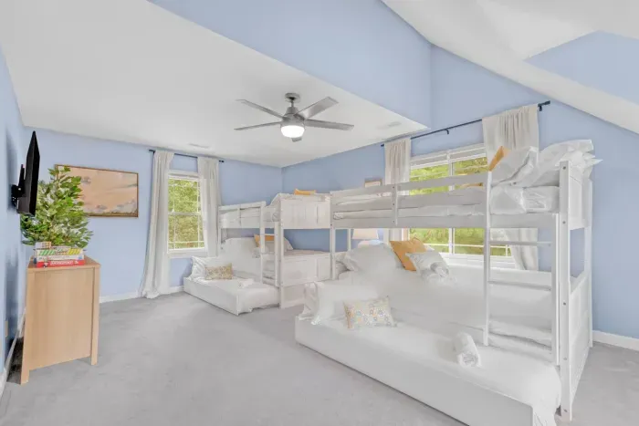 A cheerful and spacious bunk room perfect for kids or groups, featuring two bunk beds, pull-out bed or seating, and bright blue walls that create a fun, inviting atmosphere.