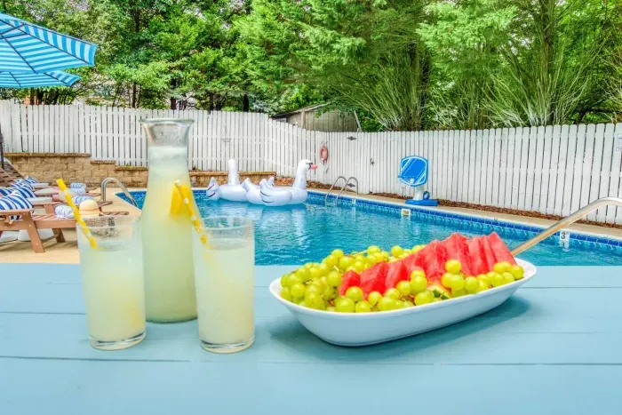 Enjoy a refreshing poolside moment with chilled lemonade and fresh fruit — the perfect setup for a relaxing afternoon under the sun.