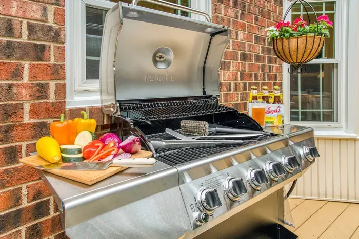 5-burner gas grill with full assortment of grilling utensils on the backyard deck.