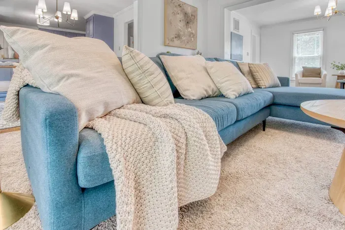 Soft blue sectional sofa with plush pillows and a knit throw—perfect for relaxing and unwinding in comfort.