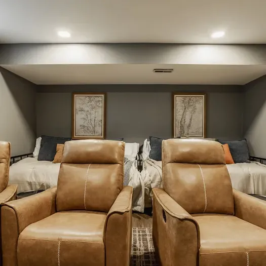 Comfortable movie room that includes beds, soft linens, and warm lighting — a perfect space for a restful night or a cozy movie marathon.