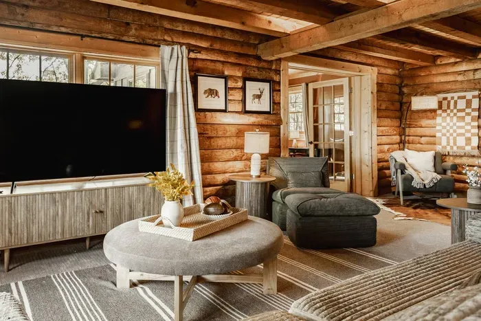 Cozy log cabin living room with warm wood interiors, plush seating, and a large TV for the perfect rustic retreat.