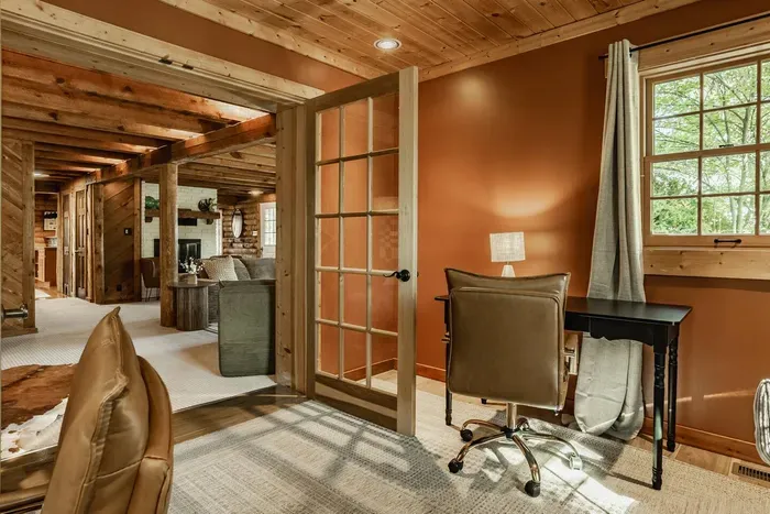 Equipped with a sleek black desk, leather chair, and large window for natural light.