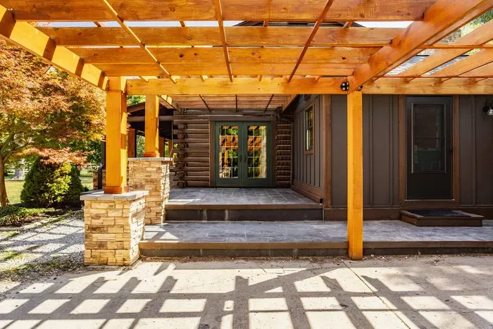 A wooden pergola and stone-accented columns, offering a seamless transition to the home’s entry.