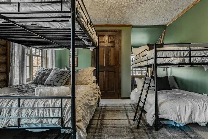 Bunk room featuring modern metal frames, soft bedding, and a rustic touch — an ideal space for kids, friends, or family.