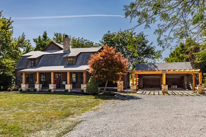 Front view featuring the house front porch and a spacious patio. The attached garage with a matching wooden pergola adds symmetry and warmth to the inviting exterior.