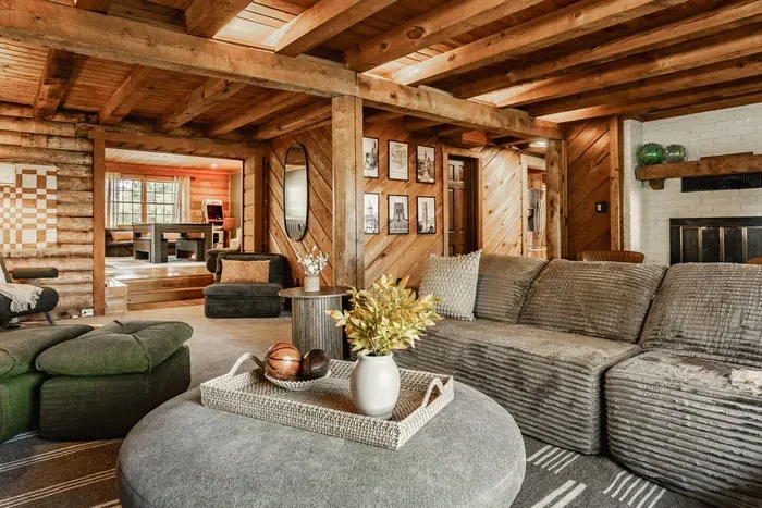 Spacious living room with plush seating, rustic beams, and open flow to the game room.