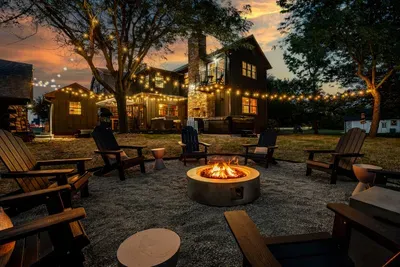Cozy fire pit area with Adirondack chairs, string lights, and a warm evening glow—perfect for relaxing or enjoying s’mores under the stars.