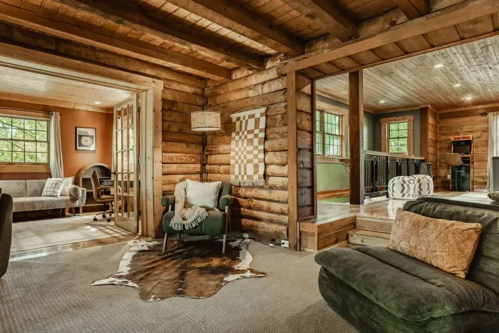Rustic log cabin with seating, exposed beams, and open flow between lounge and sitting areas.