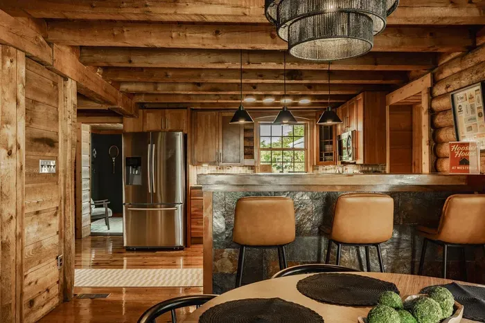 Kitchen and dining space with a stone island, wood beams, and modern pendant lighting.