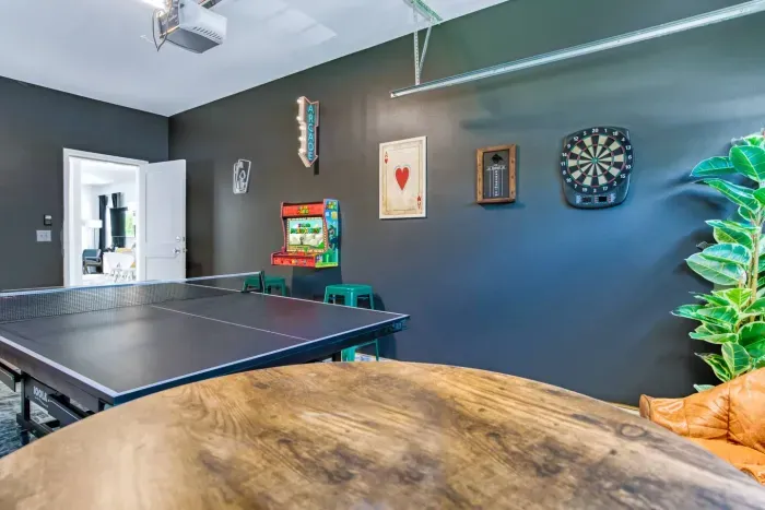 Enjoy endless fun in this vibrant game room featuring a ping pong table, retro Super Mario arcade machine, wall-mounted dartboard, and a large smart TV. 