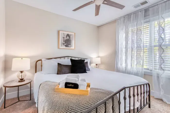 Stylish and comfortable room featuring a cozy bed, ceiling fan, streaming TV, and a dedicated desk area — perfect for work or relaxation.