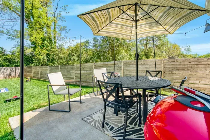 Backyard patio with outdoor dining, umbrella shade, and a grill — ideal for barbecues and relaxing outdoors.