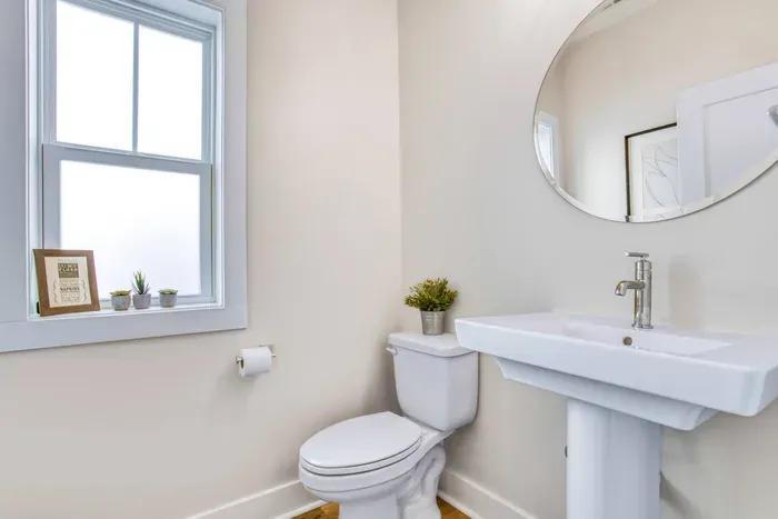 Clean and airy half bath with modern fixtures, a large mirror, and plenty of natural light.