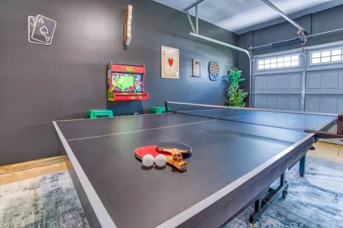 Enjoy endless fun in this vibrant game room featuring a ping pong table, retro Super Mario arcade machine, wall-mounted dartboard, and a large smart TV. 