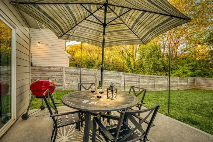 Backyard patio with outdoor dining, umbrella shade, and a grill — ideal for barbecues and relaxing outdoors.
