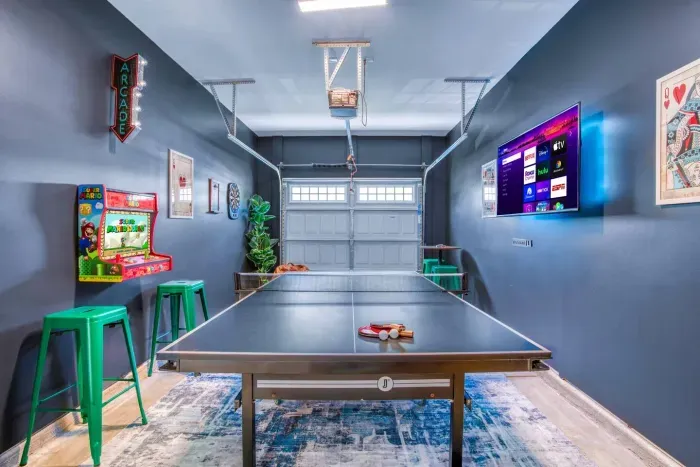 Enjoy endless fun in this vibrant game room featuring a ping pong table, retro Super Mario arcade machine, wall-mounted dartboard, and a large smart TV. 