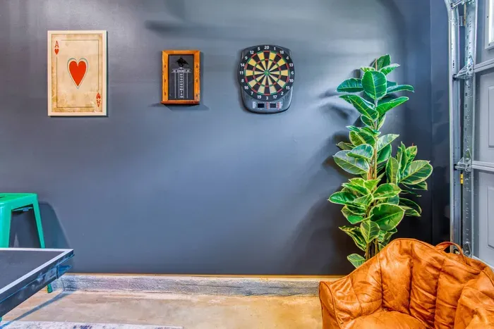 Enjoy endless fun in this vibrant game room featuring a ping pong table, retro Super Mario arcade machine, wall-mounted dartboard, and a large smart TV. 