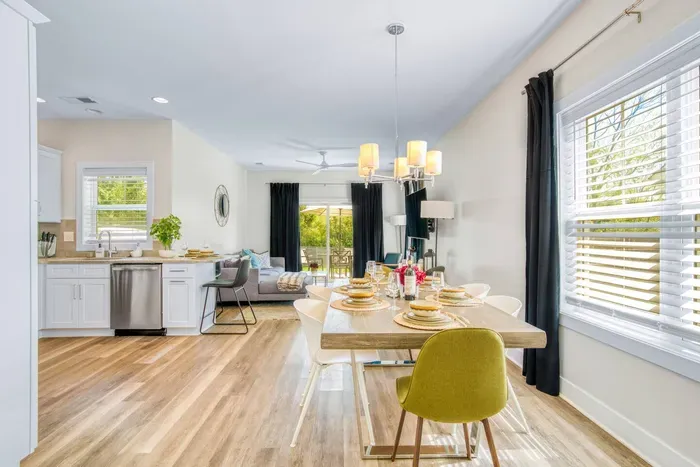 Featuring a modern wooden table, elegant lighting, and large windows that fill the space with natural light