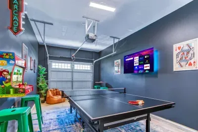 Enjoy endless fun in this vibrant game room featuring a ping pong table, retro Super Mario arcade machine, wall-mounted dartboard, and a large smart TV. 