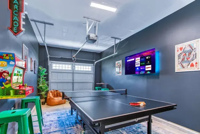 Enjoy endless fun in this vibrant game room featuring a ping pong table, retro Super Mario arcade machine, wall-mounted dartboard, and a large smart TV. 