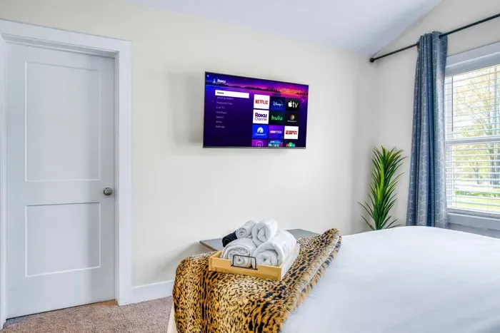 Enjoy your favorite shows on the smart TV from a cozy, well-lit bedroom with plush bedding and modern touches.