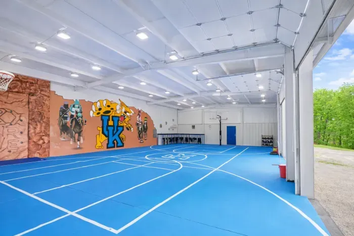 Spacious indoor sports court with hoops, mural, and lounge seating
