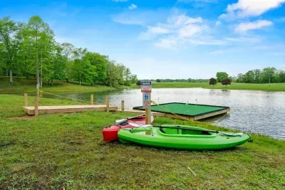 Private lake with kayaks and floating dock at a Kentucky barnhouse