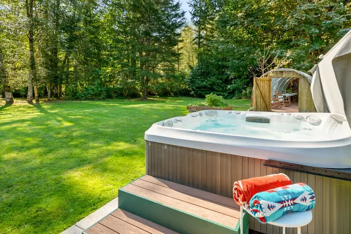 The outdoor hot tub overlooks the lawn and trees—a relaxing spot to unwind after your mountain adventures.