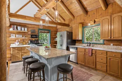 A bright kitchen with a central island, breakfast stools, and warm wood cabinetry for relaxed meals at the cabin.
