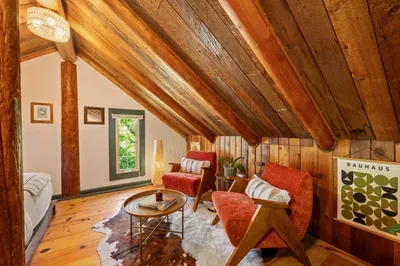 The loft sitting nook has two armchairs and a small table beneath the wood-paneled roof.