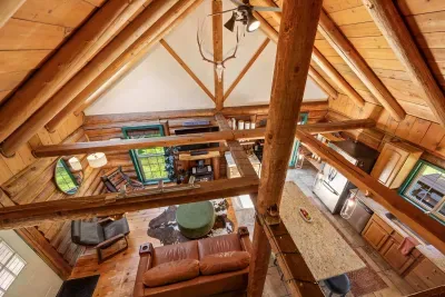 A view from the loft shows the cabin’s vaulted ceiling, exposed beams, and open living area below.