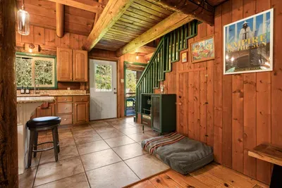 The cabin entry leads into a warm wood interior, with the staircase and living spaces close by.