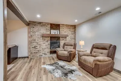 Warm, cozy electric fireplace. Remote functions for the fireplace include 5 levels of flame amount, a timer, a fire cracking sound, and 3 top light colors. The fireplace is finished off with a custom-made mantle. Two comfy reclining chairs.
