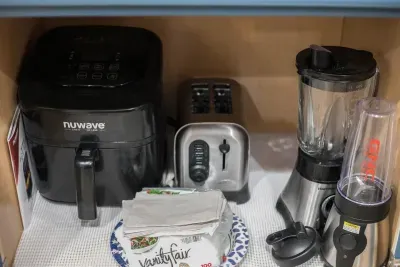Fully stocked kitchen: Nuwave air fryer with the cooking guide, Toaster, Blender, GNC blender with cups and lids. There are some paper plates, napkins, and plastic cups in this kitchen cabinet for your use.