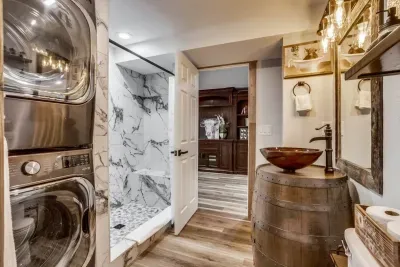 Downstairs full bathroom with washer and dryer: Includes laundry detergent and dry sheets. Extendable 2-in-1 shower head with 4 spray settings. Custom-made whiskey barrel vanity
Italian shower tile with bench. Riverstone shower floor. Custom sink