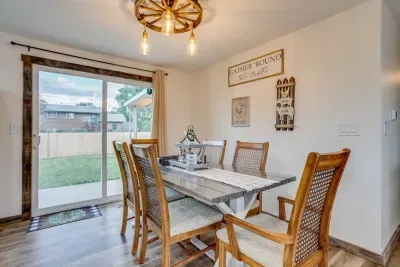 Dining room with glass sliding door into the backyard. Seating for 8 people. Custom wagon wheel light fixture. Placemats, decor table center piece, salt/pepper, beautiful farmhouse wall decor.