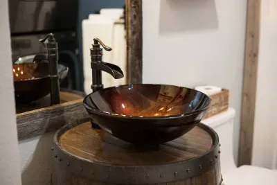 Hand crafted barrel vanity with sink bowl and a spicket faucet. Custom framed mirror.