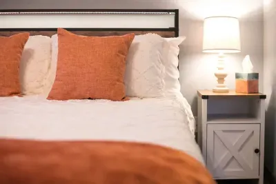 Upstairs orange bedroom: Queen Bed. Room darkening shades. Outlets USB ports and charging stations are located on the headboard. The headboard has LED lights that can be turned on via the remote located on the headboard. Lamp and nightstand.