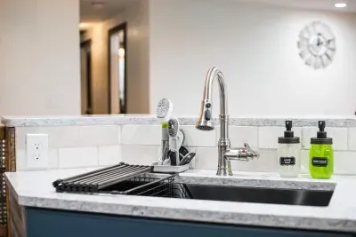 Fully stocked kitchen sink with drying rack, food washing basket, hand soap, dish soap, multiple types of dish scrubbers. Extendable sink faucet.