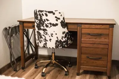 There is a desk and cow print chair for a little at-home office space in this room. Luggage rack