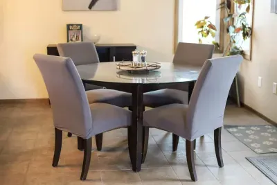Dining room with glass sliding door into the backyard. Seating for 7 people. 4 seats at the table and 3 island seating. Fully stocked dry bar. Decor table center piece, salt/pepper, and gorgeous wall decor.