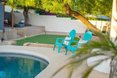 Backyard Bliss: Relax by the stunning pool, shaded by trees with a playful putting green