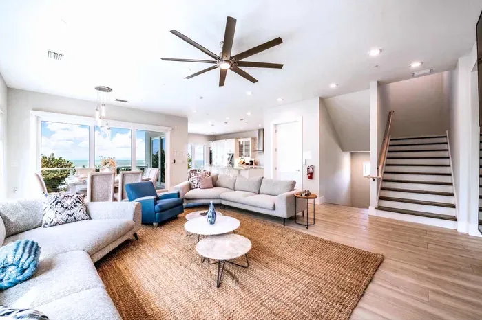 Relax in this spacious, light-filled living area featuring plush seating, modern décor, and an open layout. Perfect for gathering with family or friends, it offers comfort, style, and easy flow throughout your beautiful coastal retreat!