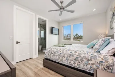 This inviting guest room offers cozy bedding, modern design, and beautiful window views — plus a TV for unwinding at night.